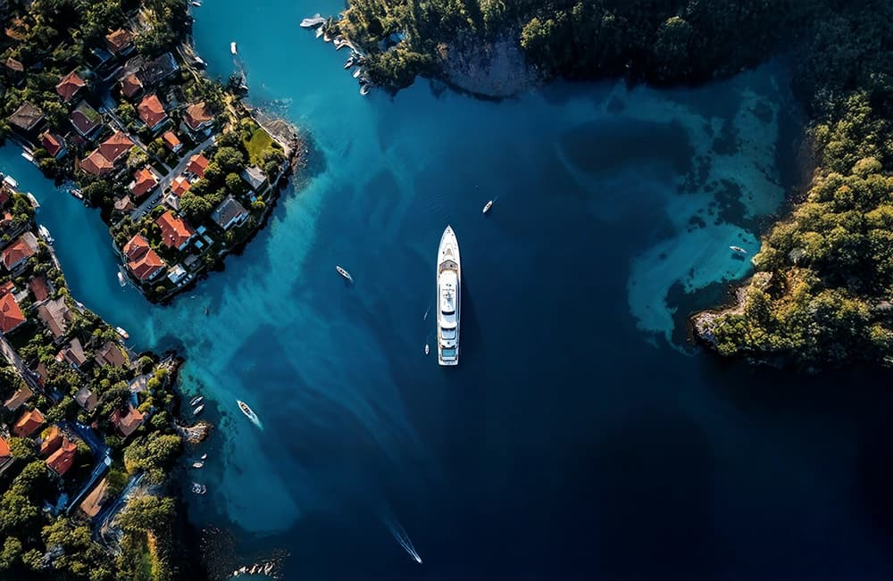 Aerial view of a yacht anchored in a turquoise cove